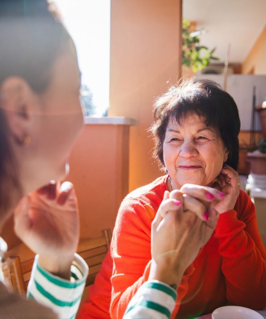 Two women hold hands and look affectionately at one another, one of them a caregiver who uses their resources to support the other